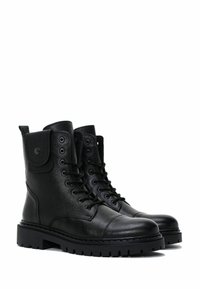 Las botas de combate de cuero negro presentan un material texturizado, un diseño con cordones, un collar acolchado y una suela gruesa con una tracción robusta.