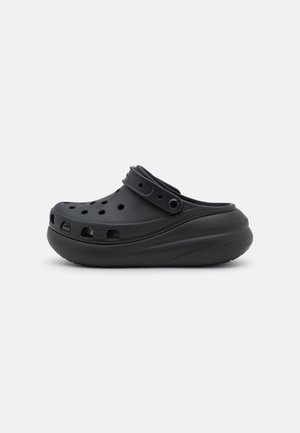 Black slip-on clog with perforations, adjustable heel strap, and thick sole, shown in side profile on white background.