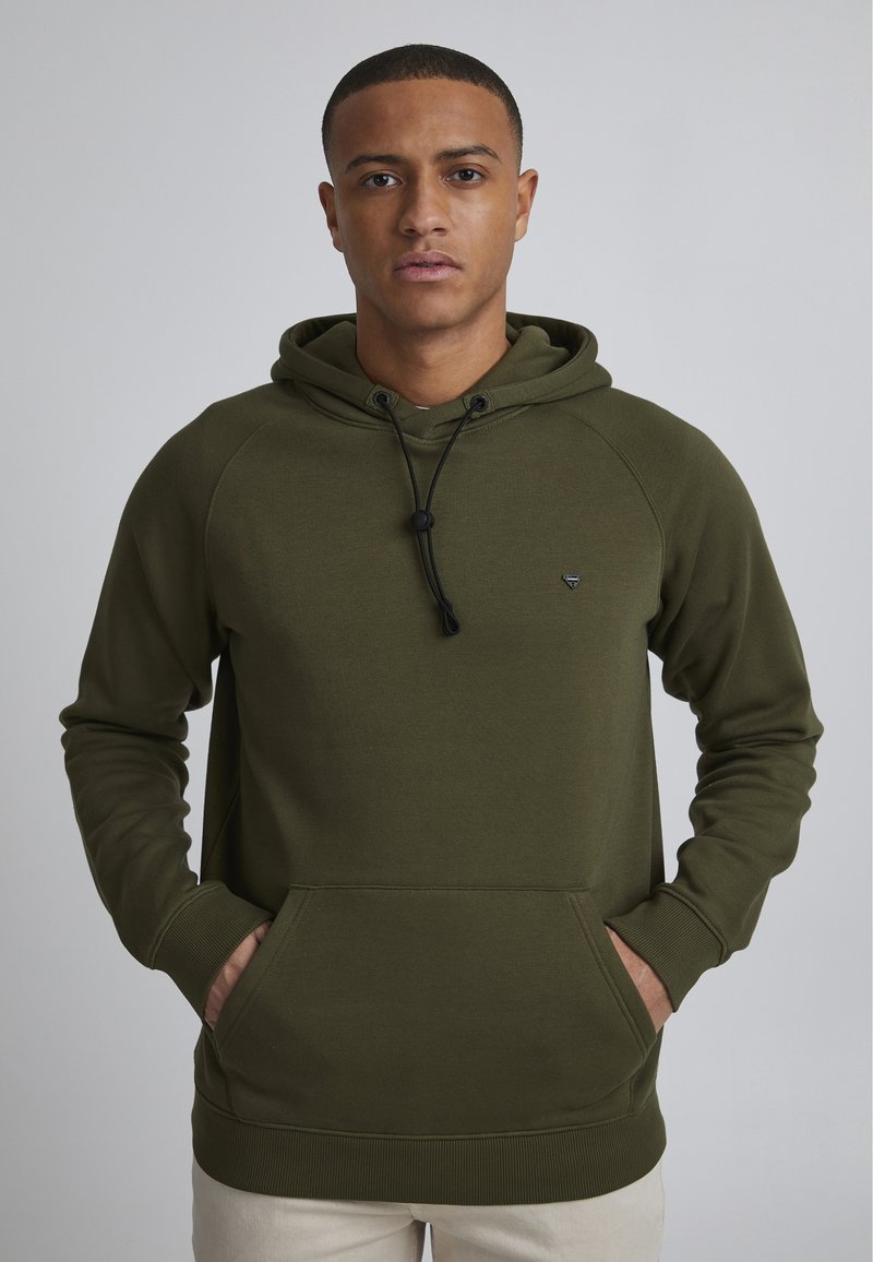 Sudadera con capucha color verde oliva, con un bolsillo frontal, cierre con cordón y puños acanalados. Presenta un pequeño logo en el pecho.