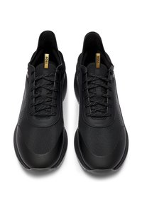 Chaussures de sport noires avec maillage texturé et panneaux synthétiques lisses, dotées de lacets noirs et d'une étiquette logo discrète sur la languette.