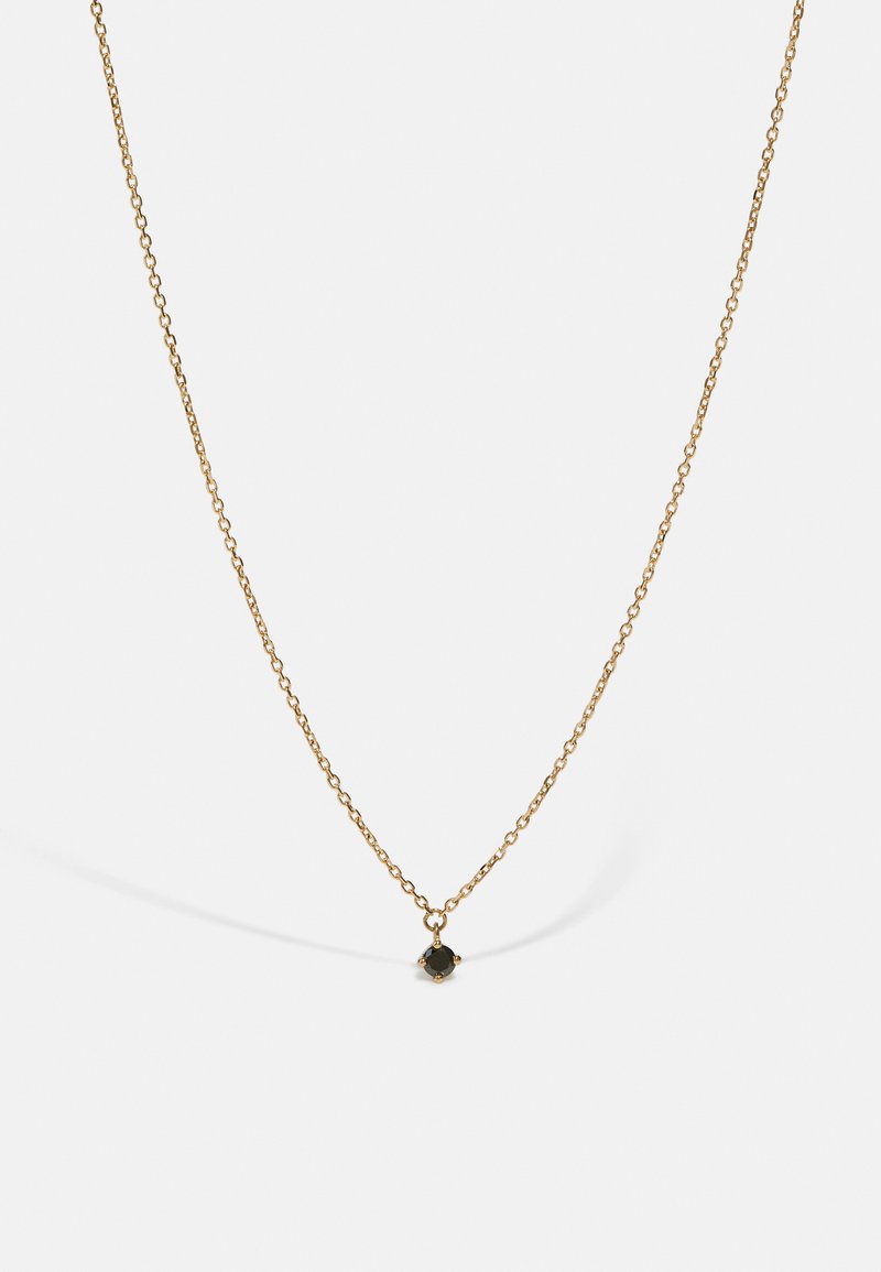 Goldene Halskette mit einem kleinen, schwarzen Tropfanhänger. Die Kette ist fein verlinkt und hat ein zartes, poliertes Finish.