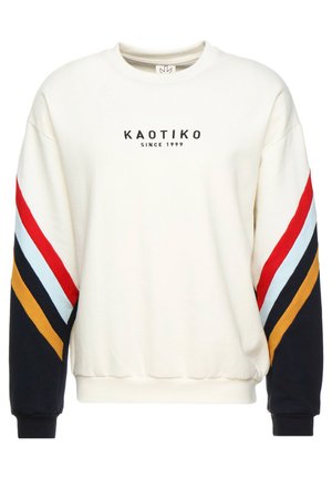 Krem genser med rund hals, som har fargede striper i rødt, blått, gult og svart langs ermene. "KAOTIKO" logoen trykket på fronten.