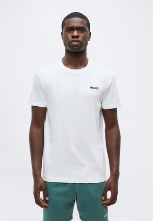 Yngre mand iført en hvid T-shirt med teksten "BORG" på brystet og grønne shorts, stående mod en ensfarvet hvid baggrund.