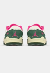 Pár nízkých tenisek s zelenou semišovou látkou, krémovými mezipodešvemi a růžovým podšívkou a logy, z pohledu zezadu na bílém pozadí.