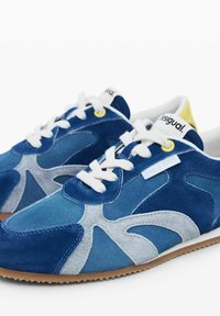 Tenisi bleumarin din suede cu accente gri, șireturi albe și un ochi galben. Caracterizat printr-un design unic cu o suprafață texturată și talpă din gumă.