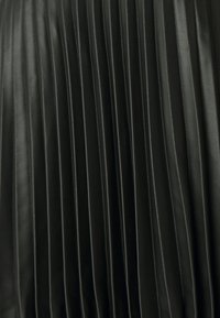 Black leather skirt featuring vertical pleats, smooth texture, and a fitted design. The surface shows a glossy finish with subtle light reflections.