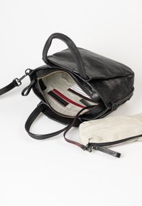 Zaino in pelle nera con apertura con cerniera, fodera a righe beige, multiple tasche interne e una pochette a righe staccabile.