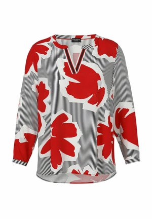 Blouse blanche avec des rayures verticales noires et de grands motifs floraux abstraits rouges, dotée d'un col en V et de manches longues.