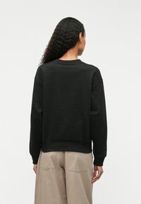 Μαύρο βαμβακερό σουέντ με στρογγυλή λαιμόκοψη, ribbed μανσέτες και χαλαρή εφαρμογή. Διαθέτει μαλακή υφή και cropped μήκος.