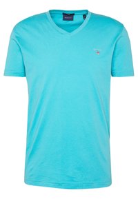Türkisfarbenes V-Ausschnitt-T-Shirt, kurze Ärmel, aus weichem Stoff. Verfügt über ein kleines GANT-Logo auf der Brust; glatte, leichte Textur.