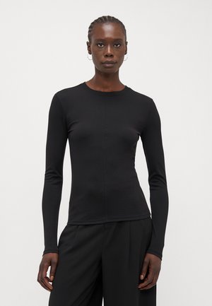 Black long-sleeve shirt with a round neckline, fitted shape, smooth texture, and minimal seam detailing, paired with black trousers.
