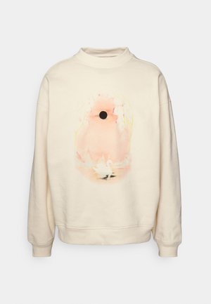 Kremowa bluza z miękkim różowym abstrakcyjnym wzorem, na którym znajduje się czarne koło oraz mały biały łabędź blisko dolnej środkowej części.