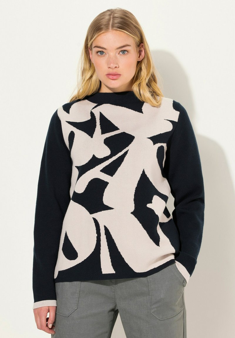 Suéter de punto en tonos navy y beige que presenta formas abstractas, cuello redondo y mangas largas. Textura suave con colores en contraste.