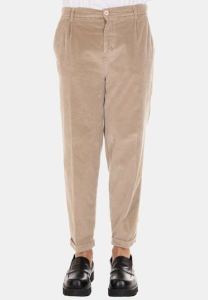 Pantaloni beige in velluto a coste con una vestibilità comoda, caratterizzati da una chiusura frontale con bottoni e risvolti alle caviglie, abbinati a scarpe slip-on nere.