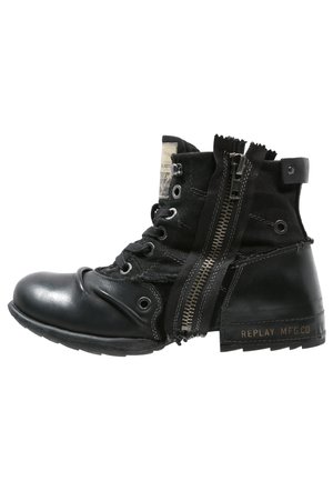 Black ankle boots featuring a combination of shiny leather and canvas, adjustable laces, side zipper, and a textured sole.