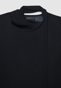 Top leggero nero con scollo drappeggiato, texture morbida e design minimale. Etichetta con la scritta "CALLIOPE," taglia "S."