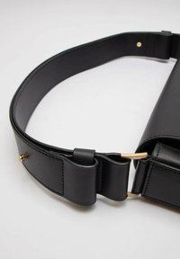 Borsa a cintura in pelle nera con texture liscia, forma curvata, dettagli in metallo dorato e una larga tracolla regolabile.