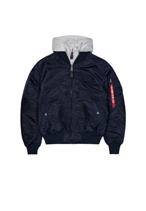 Veste de bombardier marine avec un sweat à capuche gris superposé à l'intérieur, poches zippées, poignets côtelés et une étiquette rouge "Retirer avant le vol" sur la poche de la manche.
