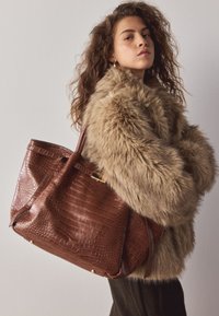 Sac cabas en cuir embossé crocodile marron avec surface texturée, deux anses d'épaule et accents en métal doré, présenté sur un fond neutre.