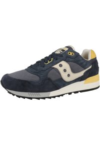 Marineblaue Wildleder- und Mesh-Sneaker mit cremefarbenen Akzenten, gelbem Absatz, schwarzer Gummisohle und auffälligem Seitenlogo mit drei kreisförmigen Ausschnitten.