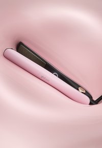 GHD Gold Haarglätter in mattem Pink mit einer schwarzen Keramikplatte, ergonomischem Design und einem runden Power-Knopf.