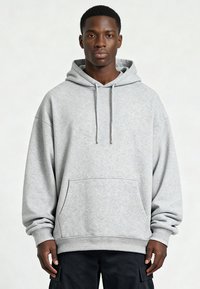 Felpa oversize grigio chiaro in cotone. Dotata di tasca frontale, cappuccio con coulisse e polsini a costine. Tessuto dalla texture liscia.