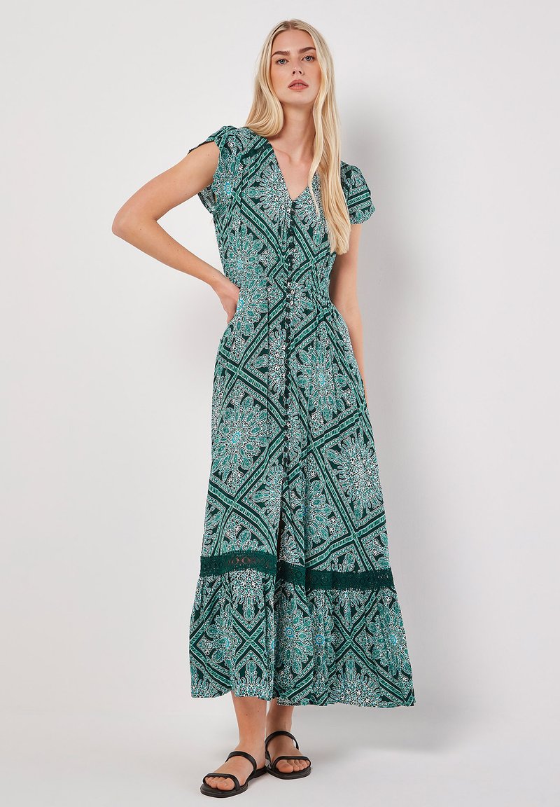 Langes, gemustertes grünes Kleid mit V-Ausschnitt, kurzen Puffärmeln und einem gestuften Saum mit Spitze. Leichter Stoff mit komplexem Design.