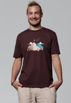 Bordeaux katoenen t-shirt met een afbeelding van bergen, bomen en een nachtlandschap met sterren en een halve maan. Korte mouwen, losse pasvorm.
