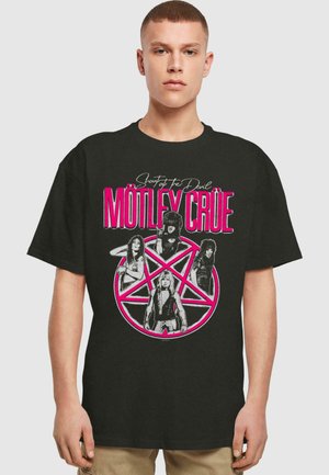 Black cotton t-shirt featuring a band graphic with pink accents, a pentagram, and four illustrated band members with a "Shout at the Devil" slogan.