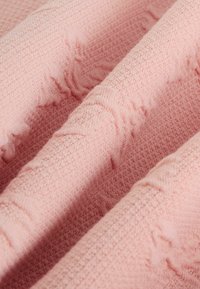 Rosa strukturierte Stoff mit einem weichen, gewebten Muster. Die Oberfläche weist dezente erhabene Details auf, die ein taktiles Erscheinungsbild erzeugen.