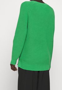 Grüner Strickpullover mit gerippter Textur, langen Ärmeln und Seitenschlitzen. Verfügt über eine lockere Passform und einen Rundhalsausschnitt.