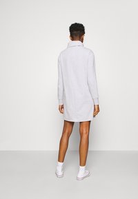 Grijze sweatshirtjurk met een kraag, lange mouwen, een ontspannen pasvorm en een lengte tot halverwege de dij. Gekocht met witte enkelkousen en schoenen.