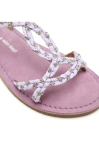 Infradito lilla con cinturini intrecciati decorati con borchie argentate, dotati di una morbida soletta in suede viola e suola marrone.