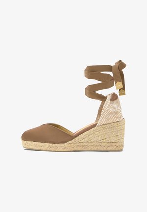 Alpargata cuña marrón con suela de yute trenzado y cordones que se atan alrededor del tobillo, con contrafuerte tejido con un patrón claro.
