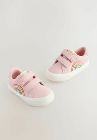 Baskets roses claires en matériau synthétique avec deux sangles Velcro, une semelle en caoutchouc blanche et un design arc-en-ciel sur le côté.