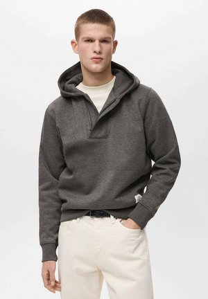 Dark gray hooded sweatshirt with a front half-zip, kangaroo pocket, and ribbed cuffs, paired with cream-colored pants.