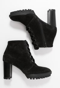 Bottines en suède noir avec un laçage à l'avant, une fermeture éclair sur le côté et des talons hauts noirs épais avec une semelle texturée.