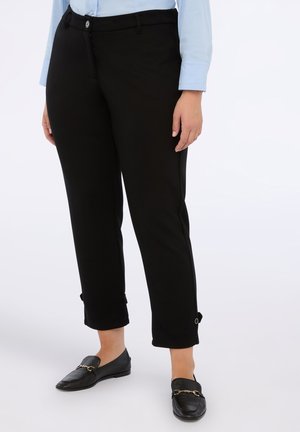 Pantalons noirs ajustés à jambe droite, avec une fermeture à bouton et des ourlets retroussés avec des accents de bouton. Texture de tissu lisse.