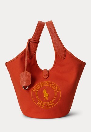 Crvena platnena torba s kožnim ručkama i logom Polo Ralph Lauren New York izvezenim žutom bojom na prednjoj strani.