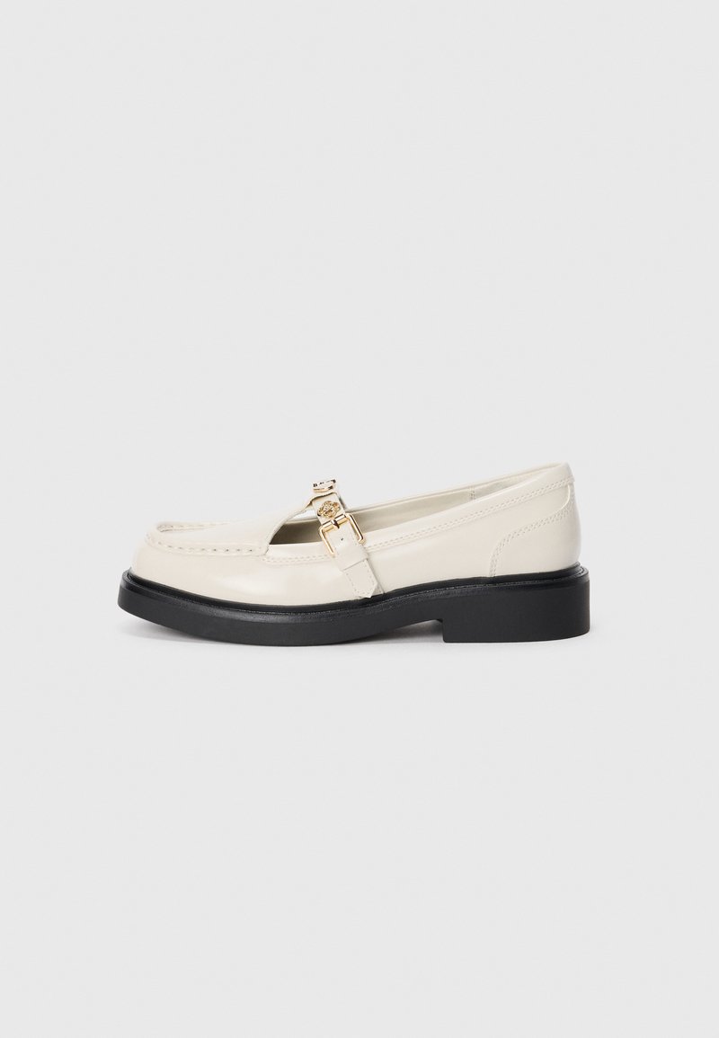 Mocassins en cuir blanc avec un bout arrondi, une petite semelle en caoutchouc noir et un détail de boucle en or. Texture lisse avec des accents de couture.