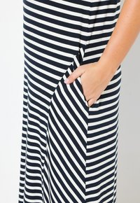 Sukienka w paski z poziomymi granatowymi i białymi pasami, wykonana z miękkiego materiału, z boczną kieszenią zintegrowaną w projekcie.