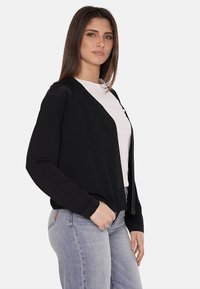 Cardigan nero a maglia con una vestibilità rilassata, apertura frontale e maniche lunghe. Presenta sottili decorazioni e una finitura testurizzata.