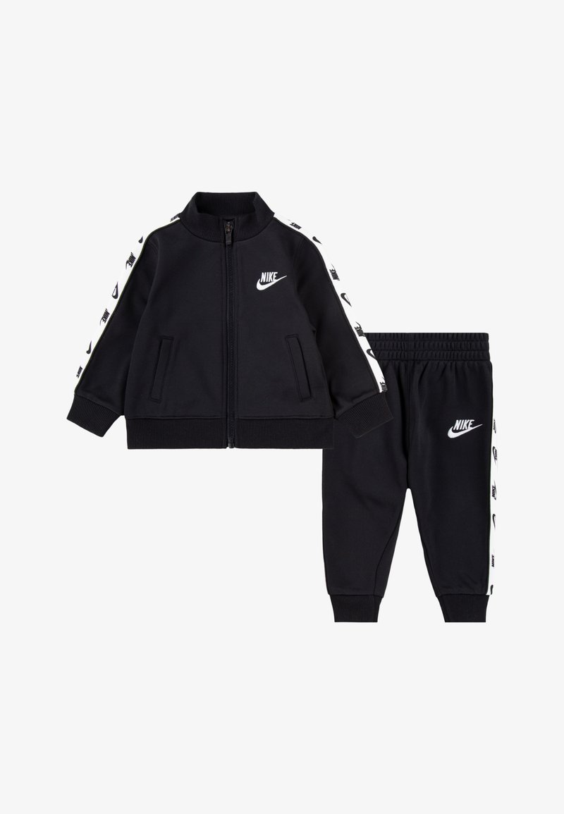 Juodas Nike treniruoklių kostiumas su užtrauktuku ir logotipu, baltais šoninėmis juostomis, derinamas su atitinkamomis kelniūmis ir suklestėjusiomis rankogaliais.