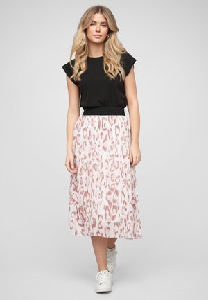 Kobieta o długich blond włosach ubrana w czarny, bezrękawnik, różowo-białą spódnicę midi w panterkę oraz białe trampki, idąca do przodu.