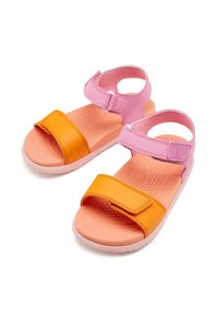 Dos sandalias con una correa superior rosa y una correa inferior naranja. Tienen una suela texturizada y cerraduras de velcro para un ajuste ajustable.