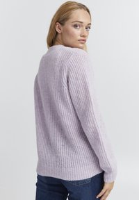 Maglione lilac lavorato a maglia con superficie testurizzata, polsini a coste e una vestibilità rilassata, abbinato a jeans in denim scuro per un look informale.