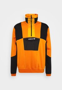 Giacca tipo pullover arancione e nera con collo alto, zip frontale e logo Adidas sul petto. Caratterizzata da un design a blocchi di colore e polsini elasticizzati.