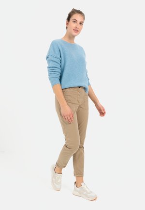 Lyseblå, struktureret striktrøje med ribbestrikkede manchetter, parret med beige, slim-fit chinos og lyse sportsko.