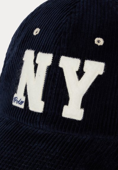 Jūras laika kordēra cepure ar baltu "NY" burtiem un mazu zilu "Polo" logo. Tekstūrēta auduma ar redzamām rievām un izšūtām akcentiem.
