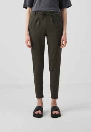 Dark green trousers with a drawstring waist, tapered fit, front pleats, and side pockets. Paired with black slide sandals.